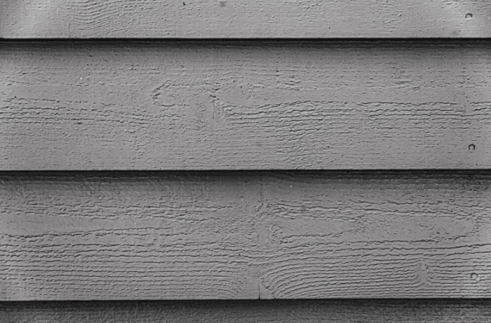 A close-up view of textured wooden siding in black and white.