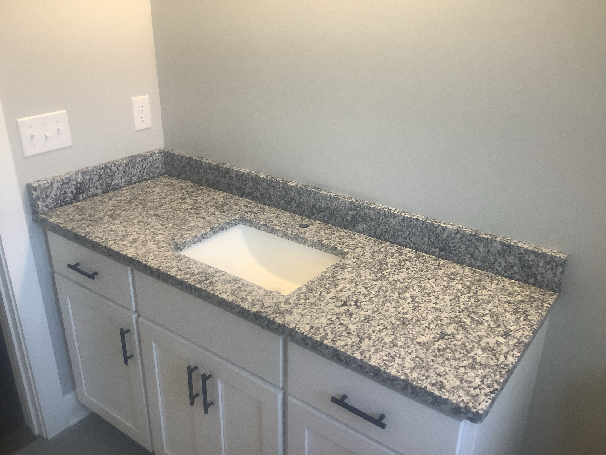 A modern bathroom with granite countertops and a stylish sink.
